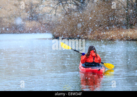 La donna è il kayak su un lago sotto la neve Foto Stock