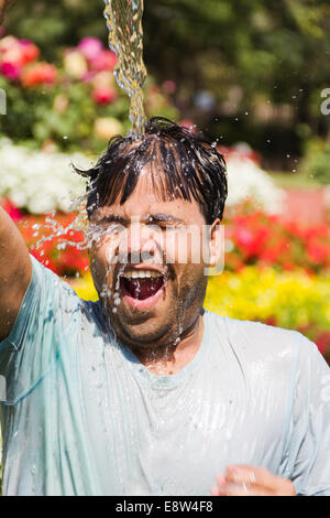 1 Uomo indiano la spruzzatura di acqua e di balneazione Foto Stock