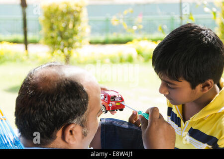 1 uomo indiano riparazione auto giocattolo con Kid Foto Stock