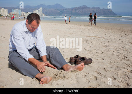 Imprenditore seduto sulla spiaggia Foto Stock