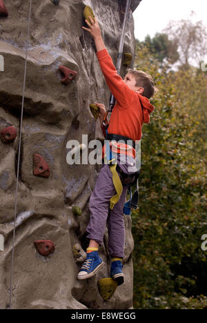 Ragazzo cerca la parete di arrampicata in una fattoria open day, blackmoor, hampshire, Regno Unito. Foto Stock