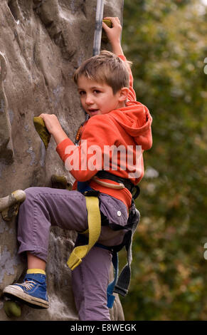 Ragazzo cerca la parete di arrampicata in una fattoria open day, blackmoor, hampshire, Regno Unito. Foto Stock