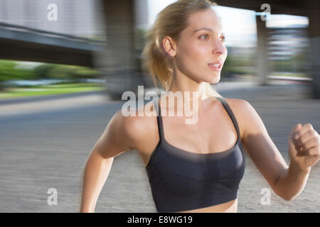 Donna che corre attraverso le strade della città Foto Stock