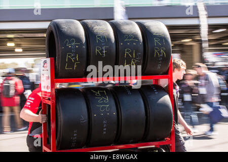 Una cremagliera di motor racing pneumatici essendo spinto lungo nella zona paddock di una pista. Foto Stock