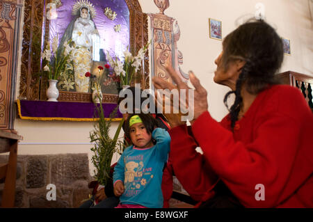 Una donna in preghiera nella chiesa di Pisac domenica giorno di mercato. Pisac. La Valle Sacra. Pisac, o Pisaq in Quechua, è una piccola città abou Foto Stock