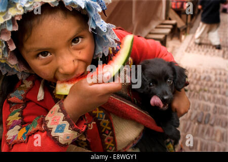 Una ragazza vestita di un costume tradizionale di mangiare un pezzo di anguria in Pisac domenica giorno di mercato. Pisac. La Valle Sacra. Pisac, o Foto Stock