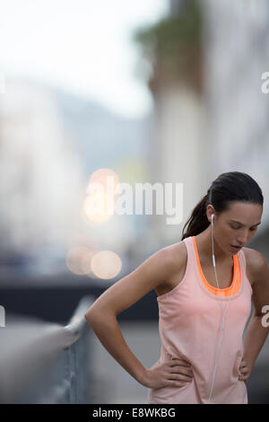 Donna in appoggio dopo marcia su strada di città Foto Stock