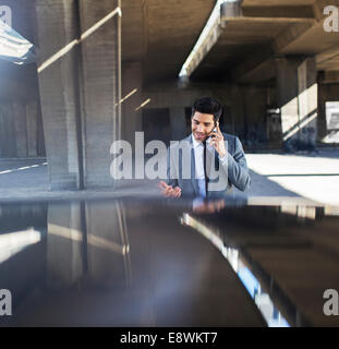 Imprenditore parlando al cellulare nel garage Foto Stock