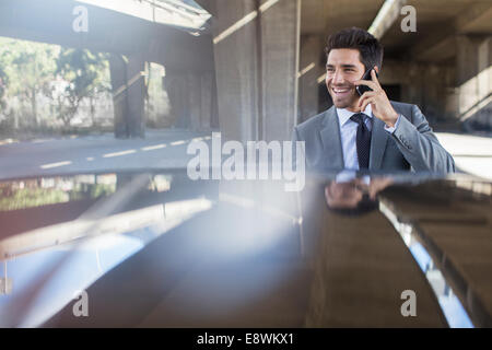 Imprenditore parlando al cellulare nel garage Foto Stock