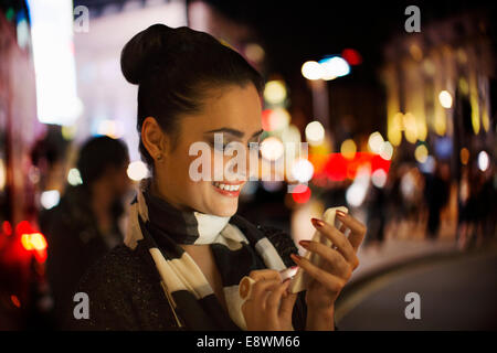 Donna che utilizza il telefono cellulare su una strada di città Foto Stock
