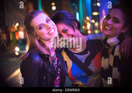 Donna sorridente insieme al di fuori del negozio di notte Foto Stock