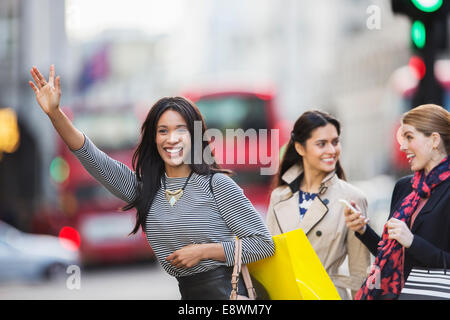 Donna che chiama il taxi con gli amici su una strada di città Foto Stock