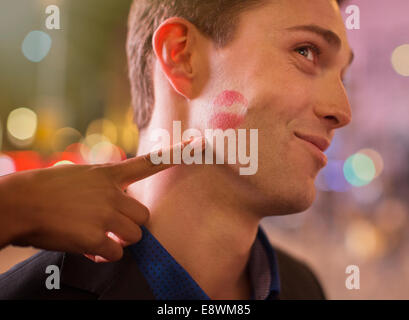 Uomo in posa con il rossetto stampa sulla guancia in città Foto Stock