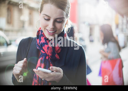 Donna che utilizza il telefono cellulare su una strada di città Foto Stock