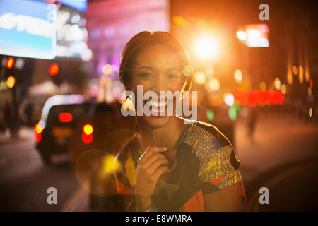 Donna sorridente su una strada di città di notte Foto Stock