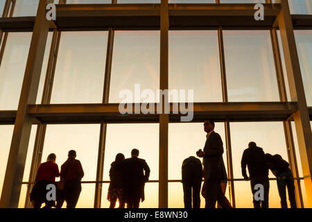 Un gruppo di persone in silhouette contro il cielo della sera guardando fuori da una finestra al di Shard, London, England, Regno Unito Foto Stock