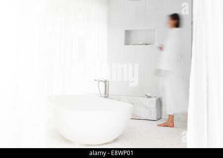 Vista offuscata della donna che cammina in una moderna stanza da bagno Foto Stock