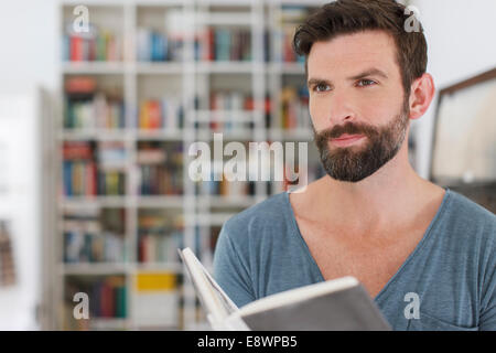 L'uomo la lettura di libro in salotto Foto Stock