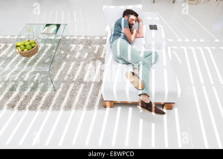 Uomo a sonnecchiare sul divano letto nel soggiorno moderno Foto Stock