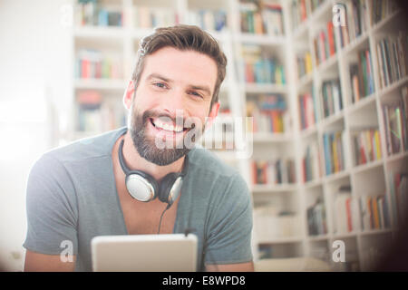 Uomo sorridente con tavoletta digitale in salotto Foto Stock