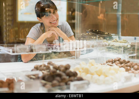 Cancelliere sorridente dietro il contatore di caramelle in negozio Foto Stock