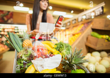 Donna controllo elenco della spesa nel negozio di alimentari Foto Stock