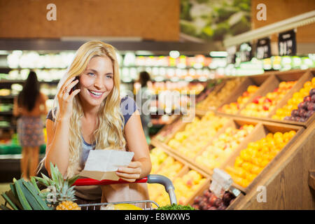 Donna che parla al cellulare in negozio di alimentari Foto Stock