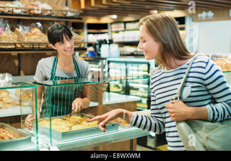 Addetto di servire il cliente a deli contatore nel negozio di alimentari Foto Stock