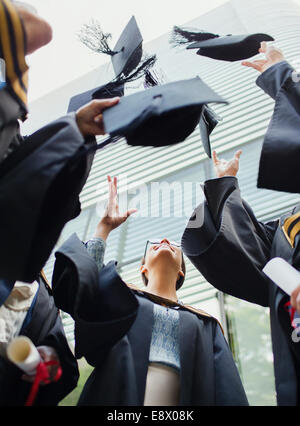 Gli studenti in abiti di gettare i tappi in aria Foto Stock