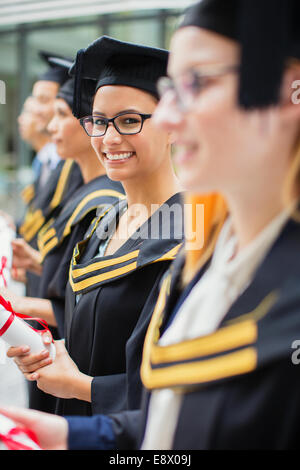 Studente nel cappuccio e camice in piedi con le scuole Foto Stock