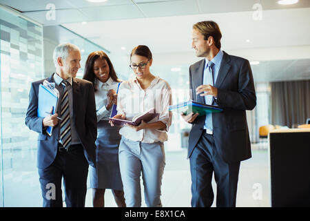 La gente di affari di parlare e camminare attraverso la costruzione di ufficio Foto Stock