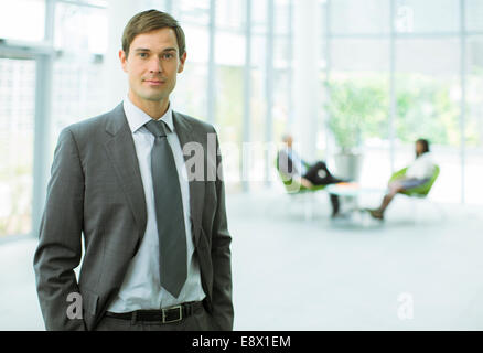 Imprenditore in piedi in edificio per uffici Foto Stock