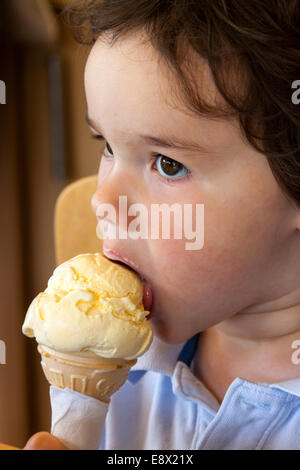 Giovane ragazzo a mangiare il gelato cornet Foto Stock