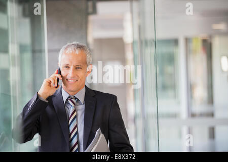 Imprenditore parlando al cellulare in edificio per uffici Foto Stock