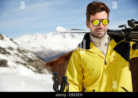 Uomo che porta sci sulla cima della montagna Foto Stock