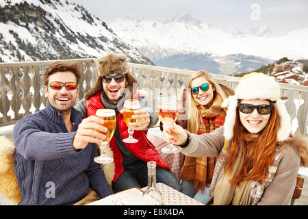 Amici celebrando con bevande nella neve Foto Stock