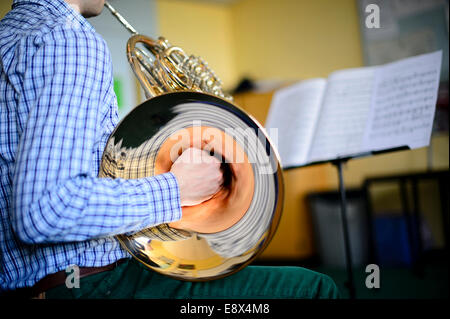 Un giovane adolescente musicista maschio pratica riproduzione di corno francese, parte di Aberystwyth Arts Center's MusicFest 2014 Foto Stock