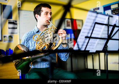 Un giovane adolescente musicista maschio pratica riproduzione di corno francese, parte di Aberystwyth Arts Center's MusicFest 2014 Foto Stock