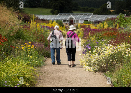 Visita estiva a Helmsley Walled Garden & 2 visitatori (giovane) a piedi sul percorso, guardando a bellissimi fiori sui confini - North Yorkshire, Inghilterra, Regno Unito.