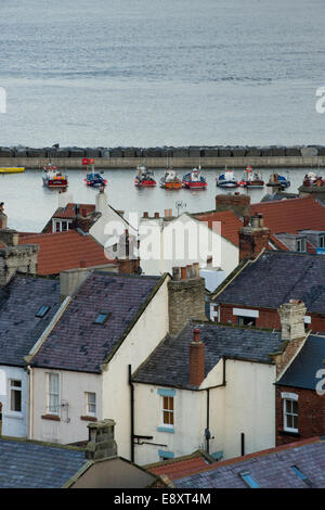 Alta vista sopra i tetti di minuscoli, pittoreschi cottage, per le barche nel porto e al di là del mare - villaggio sul mare di Staithes, North Yorkshire, Inghilterra, Regno Unito. Foto Stock