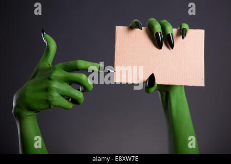 Green monster mano con unghie nere puntando sul pezzo di cartone, tema Halloween Foto Stock