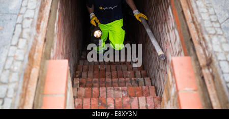 Berlino, Germania. Xvi oct, 2014. Un lavoratore passeggiate fino al di fuori della rete fognaria a Berlino, Germania, 16 ottobre 2014. La griglia, che bloccano le fognature per impedire che le persone in fuga a Berlino Ovest in sotterraneo, è ancora lì. Credito: dpa picture alliance/Alamy Live News Foto Stock