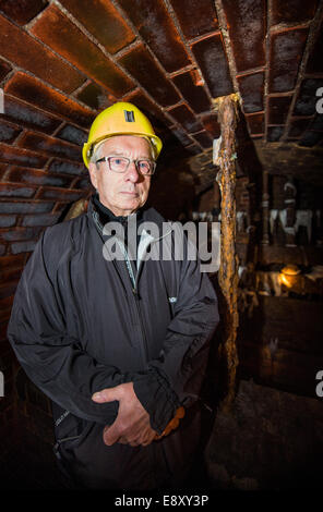 Berlino, Germania. Xvi oct, 2014. Escapee Ulrich Pfeifer (79) sorge in una fognatura a Berlino, Germania, 16 ottobre 2014. Pfeifer è stato in grado di sfuggire ad ovest con cinque studenti nel 1961. La griglia, che bloccano le fognature per impedire che le persone in fuga a Berlino Ovest in sotterraneo, è ancora lì. Credito: dpa picture alliance/Alamy Live News Foto Stock