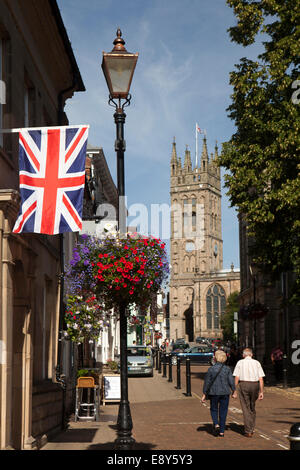 Regno Unito, Inghilterra, Warwick, Church Street, unione bandiera che baside floreali cesta appesa sulla vecchia lampada posta Foto Stock