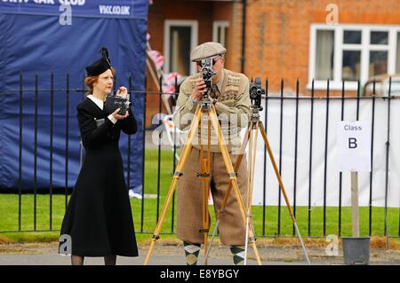 Un uomo e una donna matura in venti periodo operativo abbigliamento e periodo di caricamento fotocamere con pellicola in corrispondenza di un evento a Brooklands Museum Foto Stock