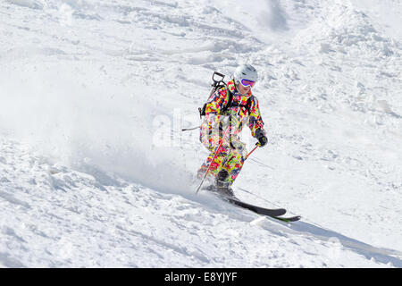 Sciatore sul pendio montano i fuori pista in neve soffice in una giornata di sole Foto Stock