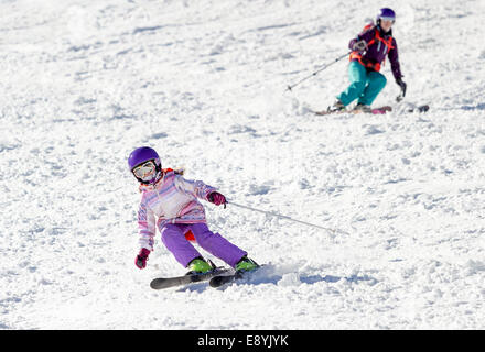 Bambina con gli sci in neve soffice sotto la cura di mia madre in una giornata di sole in montagna Foto Stock