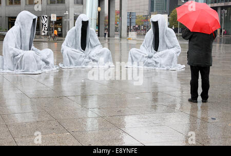 Berlino, Germania. Xvi oct, 2014. Un uomo cammina passato l'installazione "Waechter der Zeit" (lit. custodi del tempo) a Potsdamer Platz a Berlino, Germania, 16 ottobre 2014. Le tre sculture sono visualizzati come parte del "Festival delle Luci' fino al 19 ottobre 2014. Foto: Stephanie Pilick/dpa/Alamy Live News Foto Stock