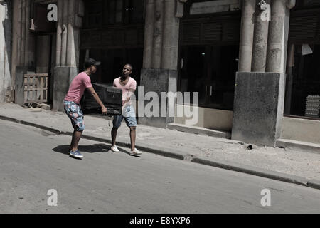 Due persone locali che trasportano un televisore nel centro di Avana, Cuba Foto Stock
