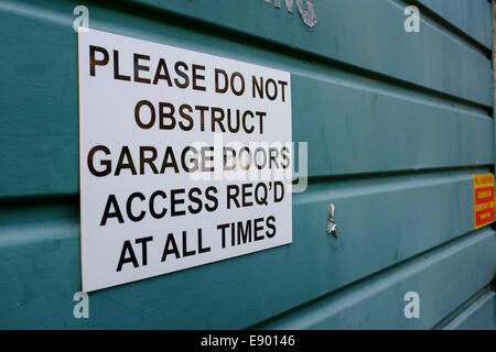 Porta di Garage segno "Si prega di non ostruire le porte del garage accesso richiesta in corrispondenza di tutti i tempi" su un grenn/blu porta di garage. Formato orizzontale Foto Stock